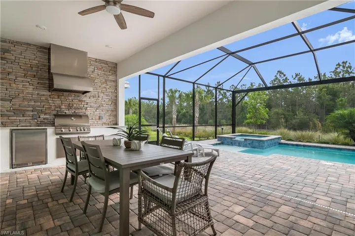 View of patio with a ceiling fan, a lanai, a pool with connected hot tub, and outdoor dining space