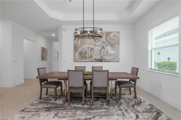 Dining area featuring a raised ceiling, plenty of natural light, and a chandelier