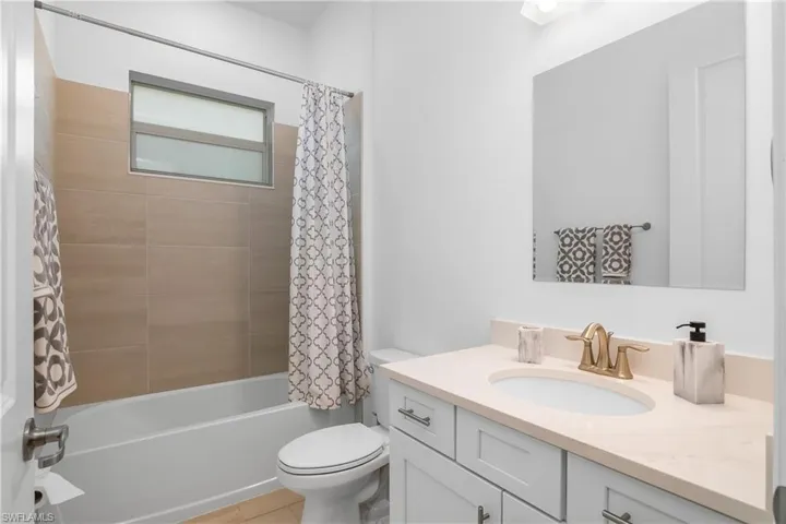 Bathroom featuring vanity, toilet, shower / bathtub combination with curtain, and tile patterned flooring
