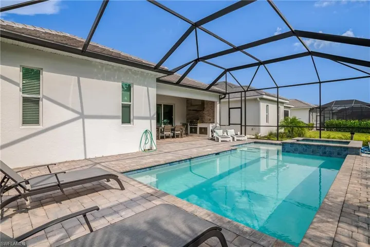 View of swimming pool with a patio, a pool with connected hot tub, a lanai, and outdoor dining area