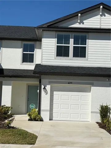 Traditional-style house featuring stucco siding, an attached garage, and a shingled roof
