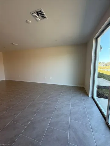 Empty room with baseboards and light tile patterned floors