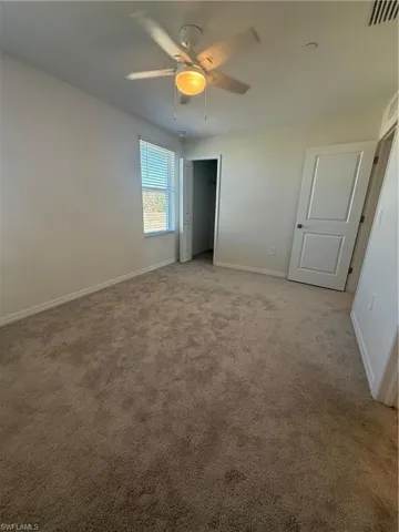 Unfurnished bedroom with light carpet and a ceiling fan