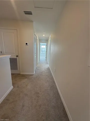 Hallway featuring light carpet and baseboards