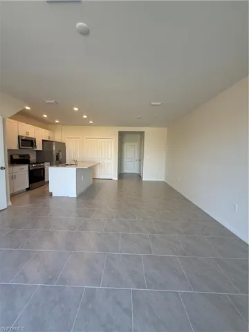 Kitchen featuring stove, a center island with sink, white cabinets, open floor plan, and recessed lighting