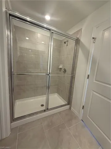 Full bath featuring a shower stall, recessed lighting, and light tile patterned floors
