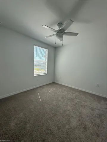 Carpeted spare room with baseboards and a ceiling fan