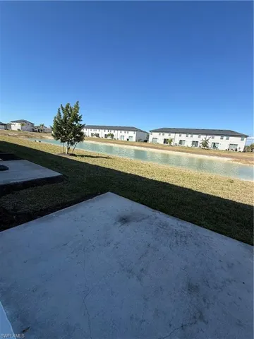 View of green lawn with a patio area and a water view