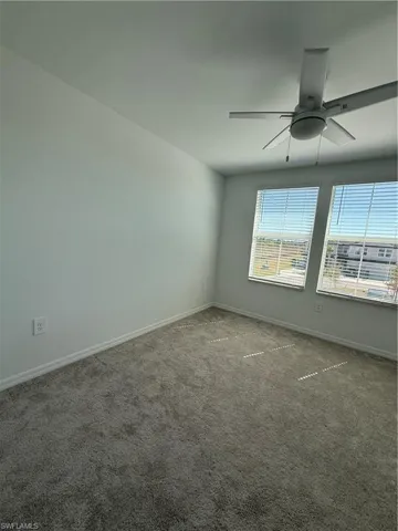 Empty room featuring carpet flooring and a ceiling fan