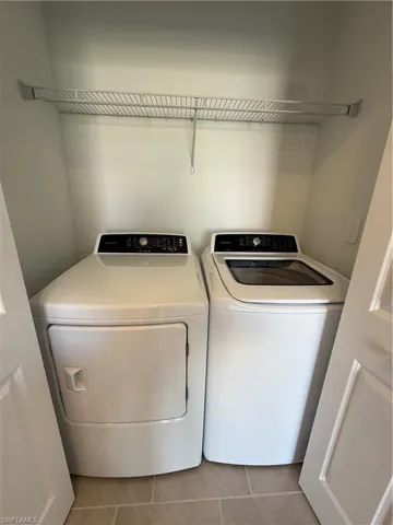 Laundry area with tile patterned flooring and washing machine and dryer