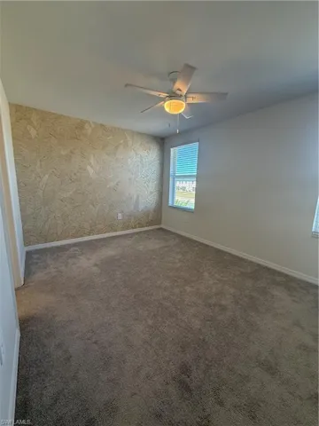 Unfurnished room featuring wallpapered walls, carpet flooring, and a ceiling fan