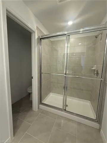 Full bath with a stall shower and light tile patterned flooring