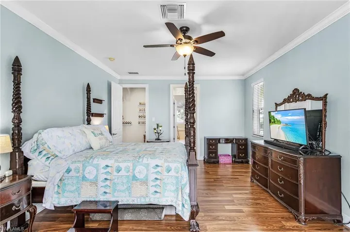 Bedroom featuring crown molding, wood finished floors, ceiling fan, and connected bathroom