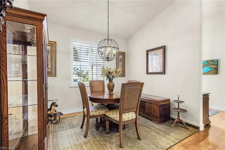 Dining room with light wood-style flooring, vaulted ceiling, and a chandelier