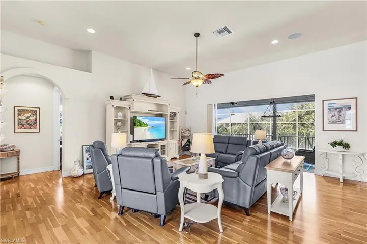 Living room featuring light wood-style floors, recessed lighting, ceiling fan, and arched walkways