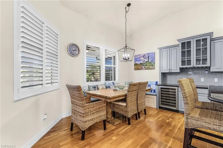 Dining space with wine cooler, light wood-type flooring, lofted ceiling, and a chandelier