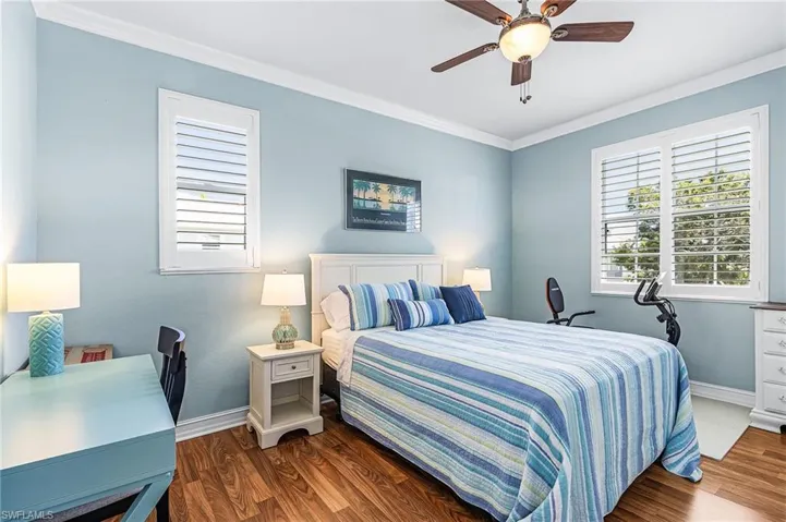 Bedroom with ornamental molding, dark wood-style floors, multiple windows, and ceiling fan