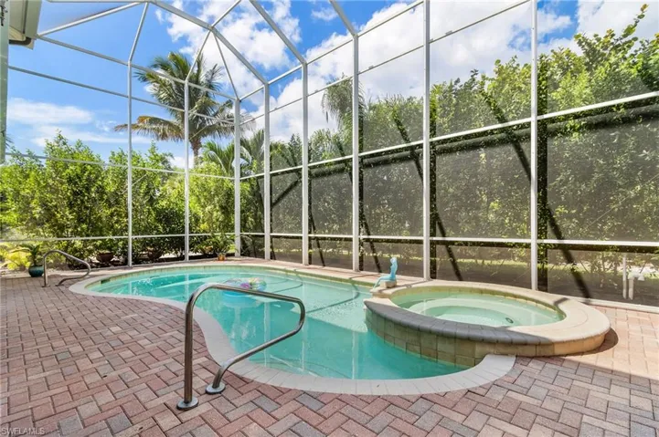 View of swimming pool featuring a lanai, a pool with connected hot tub, a sunroom, and a patio