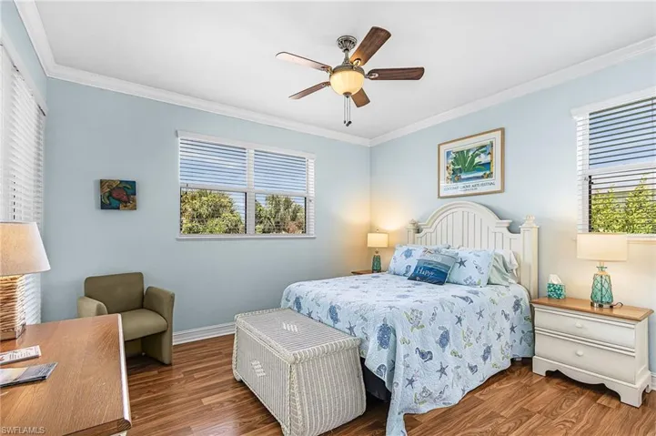 Bedroom with ornamental molding, dark wood-style flooring, and a ceiling fan