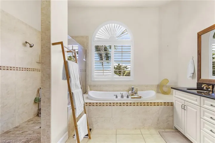 Full bath with a garden tub, healthy amount of natural light, light tile patterned flooring, and vanity