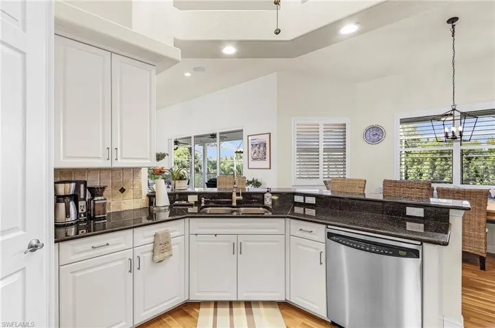 Kitchen with recessed lighting, a peninsula, white cabinetry, stainless steel dishwasher, and light wood-style flooring