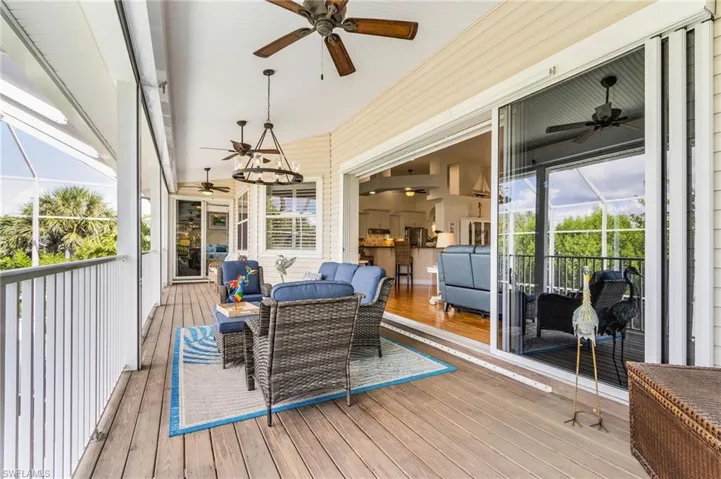 Wooden terrace featuring a sunroom, ceiling fan, and a lanai