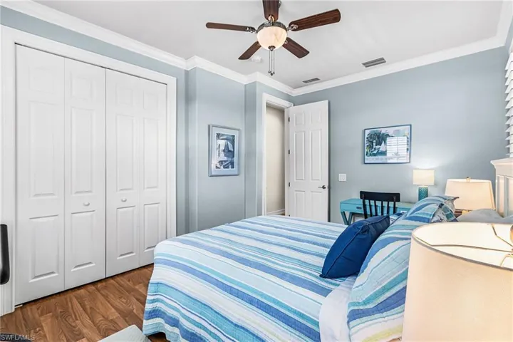 Bedroom with crown molding, wood finished floors, a ceiling fan, and a closet