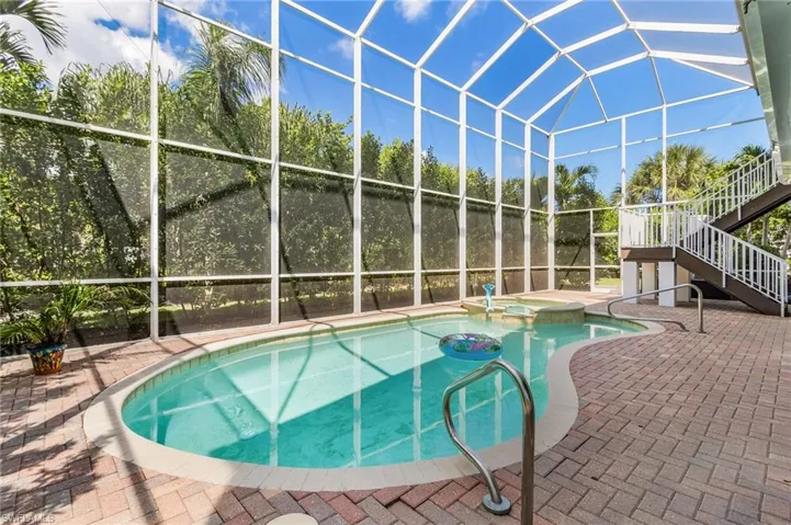 View of pool with stairway, glass enclosure, a pool with connected hot tub, a sunroom, and a patio