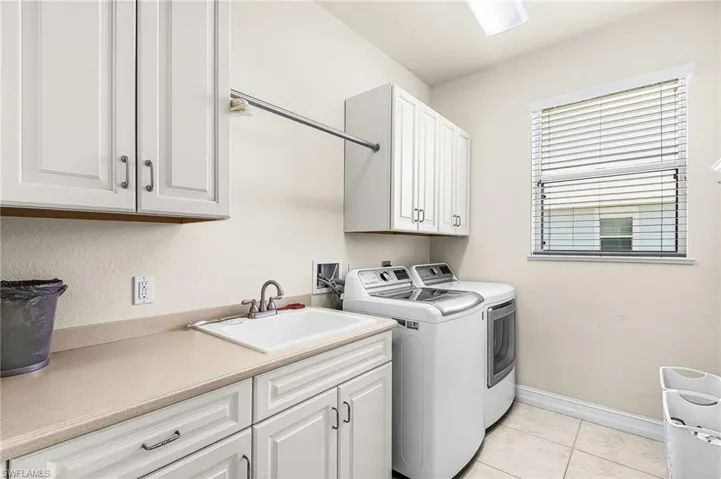 Laundry area with cabinet space, light tile patterned flooring, and separate washer and dryer