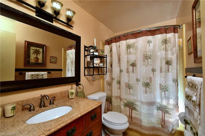 Bathroom featuring toilet, vanity, and walk in shower