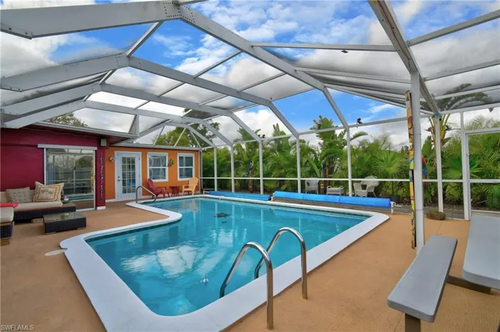View of pool with a patio, glass enclosure, and an outdoor hangout area