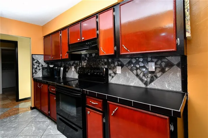 Kitchen with tasteful backsplash and black electric range oven