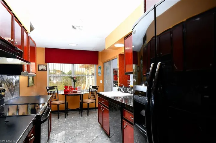 Kitchen featuring light tile patterned floors, sink, and black appliances