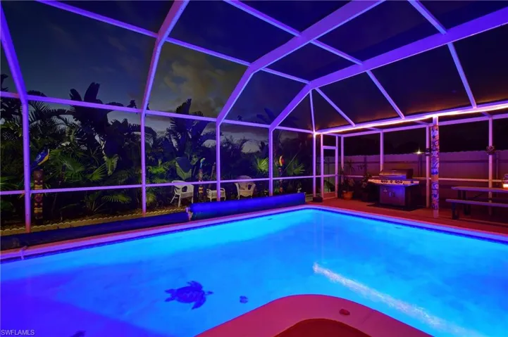 Pool at twilight with glass enclosure and a patio