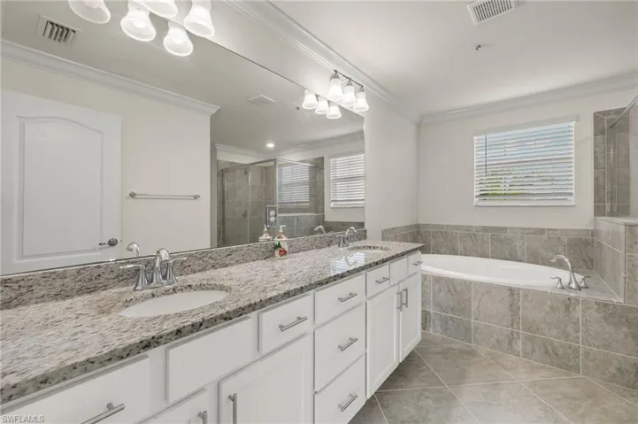 Bathroom featuring independent shower and bath, vanity, crown molding, and tile patterned flooring