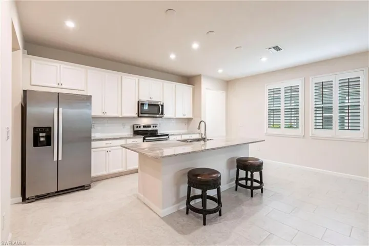 Kitchen featuring white cabinetry, stainless steel appliances, sink, and a kitchen island with sink