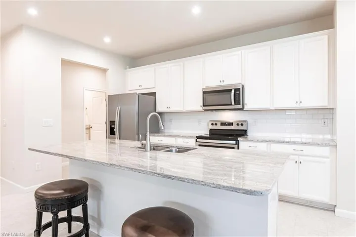 Kitchen featuring white cabinetry, sink, a kitchen island with sink, and appliances with stainless steel finishes