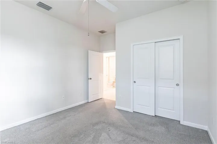 Unfurnished bedroom with light carpet, ceiling fan, and a closet
