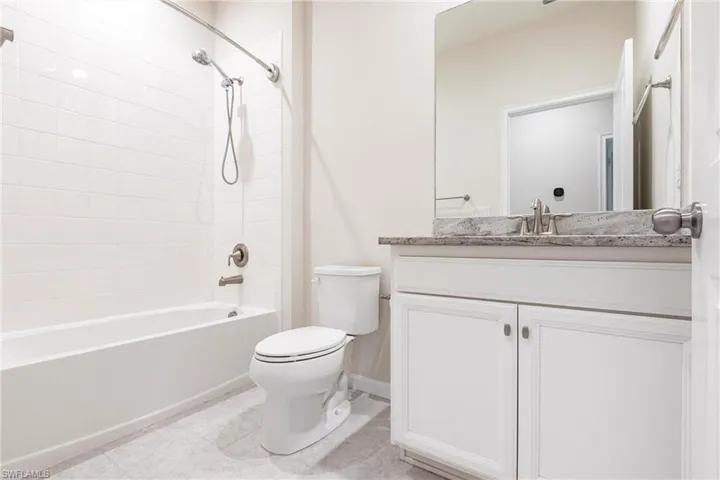 Full bathroom with vanity, tile patterned flooring, toilet, and tiled shower / bath
