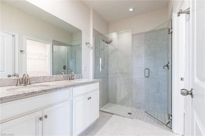 Bathroom with tile patterned floors, vanity, and a shower with door