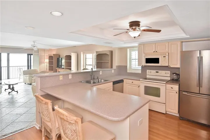 Kitchen with a ceiling fan, stainless steel appliances, open floor plan, a breakfast bar, and cream cabinetry