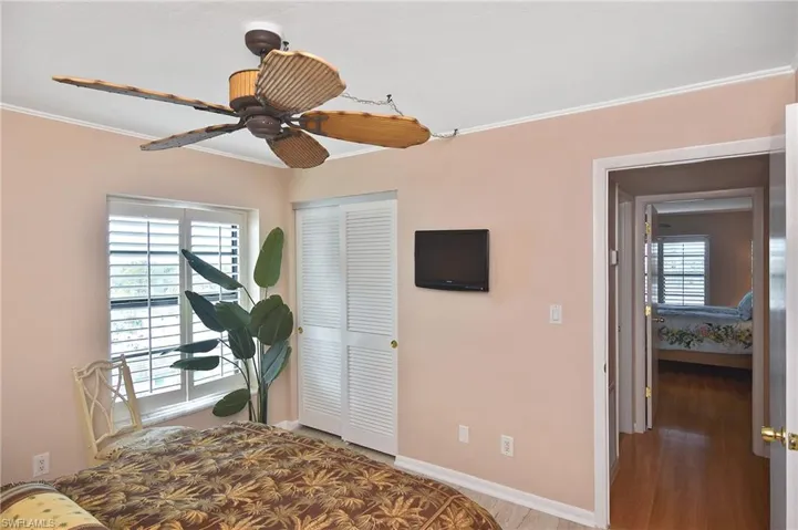 Bedroom with light wood-style flooring, ceiling fan, crown molding, and a closet