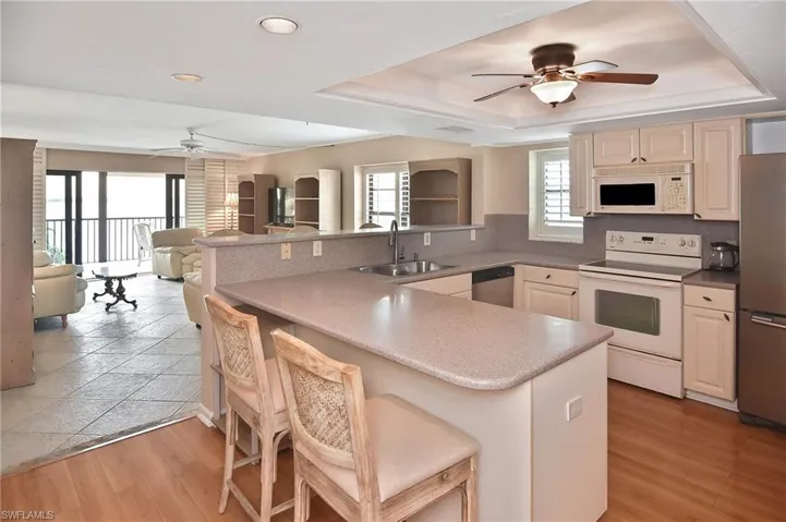 Kitchen featuring ceiling fan, stainless steel appliances, a breakfast bar, open floor plan, and cream cabinets