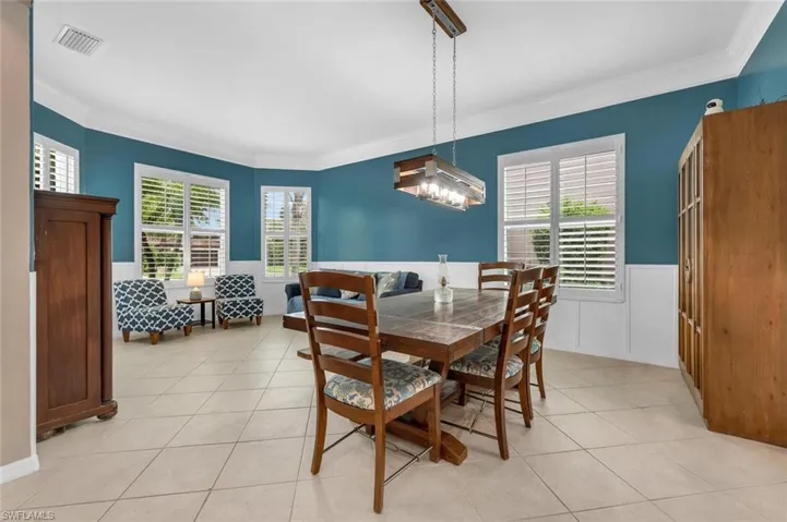 Dining space featuring ornamental molding, light tile patterned floors, and wainscoting