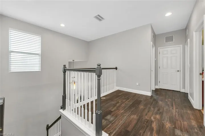 Hall with an upstairs landing, recessed lighting, and dark wood-style floors