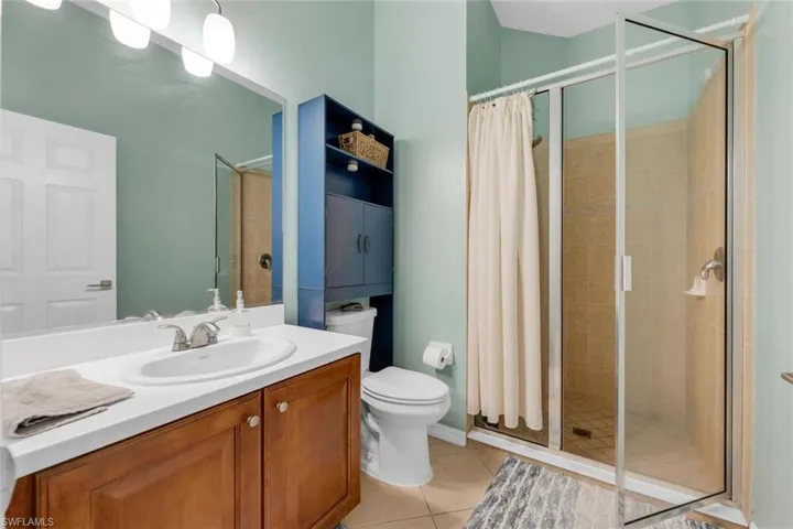 Bathroom with a shower stall, light tile patterned flooring, and vanity