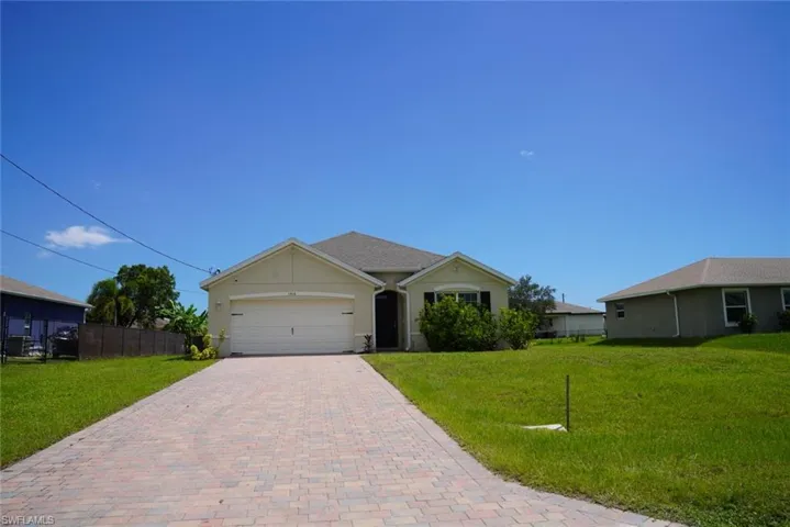 Ranch-style house with an attached garage, decorative driveway, and stucco siding