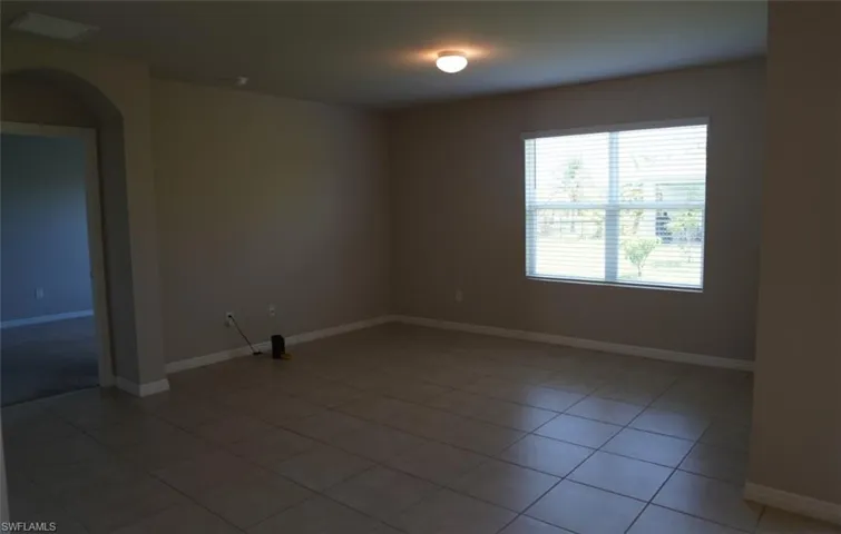 Spare room with arched walkways and light tile patterned floors
