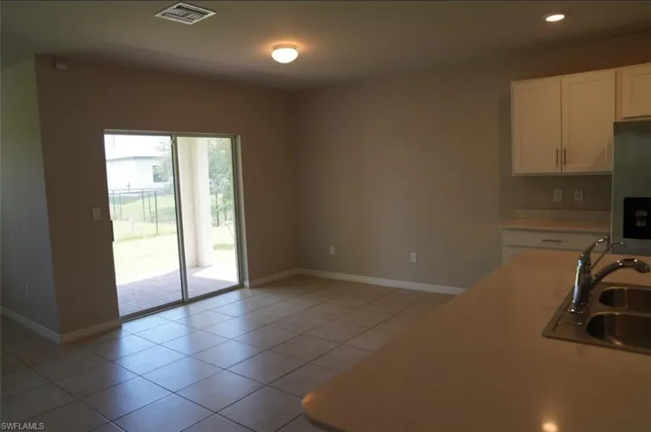 Kitchen with white cabinetry, light tile patterned floors, light countertops, stainless steel fridge with ice dispenser, and recessed lighting