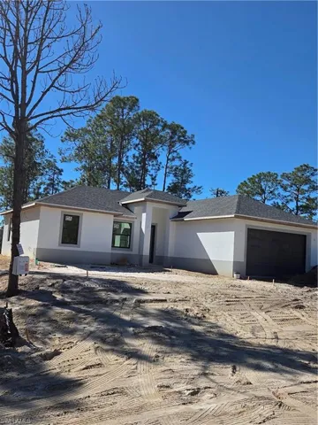 View of front of house with stucco siding, roof with shingles, driveway, and a garage